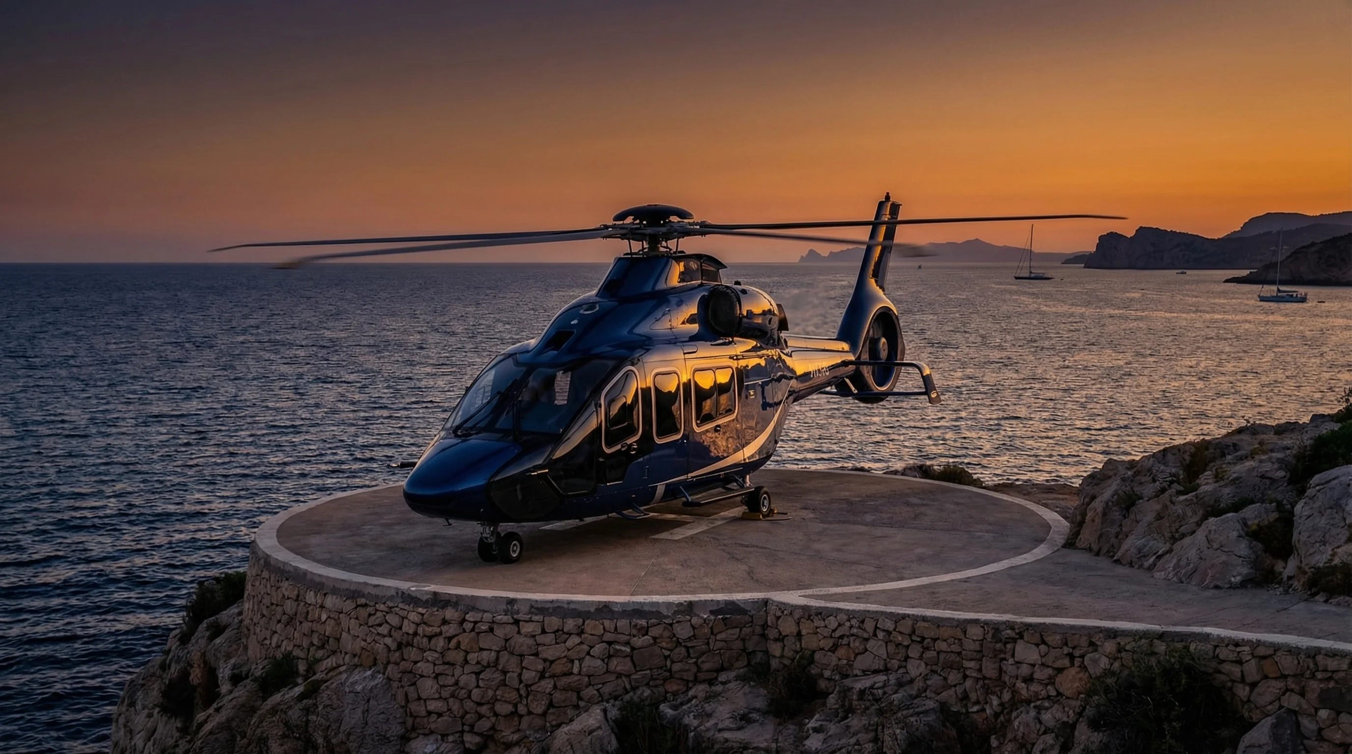 Twin-engine helicopter on a coastal clifftop helipad at sunset
