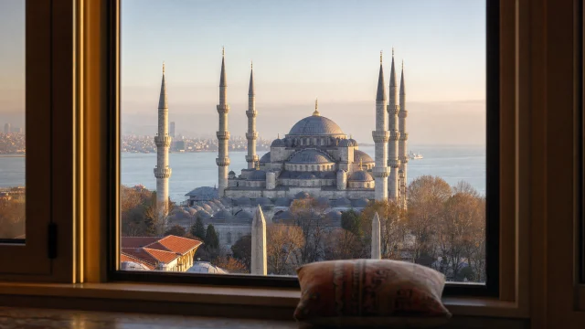 An Istanbul Imperial mosque with six minarets viewed from a high-rise residence window at golden hour