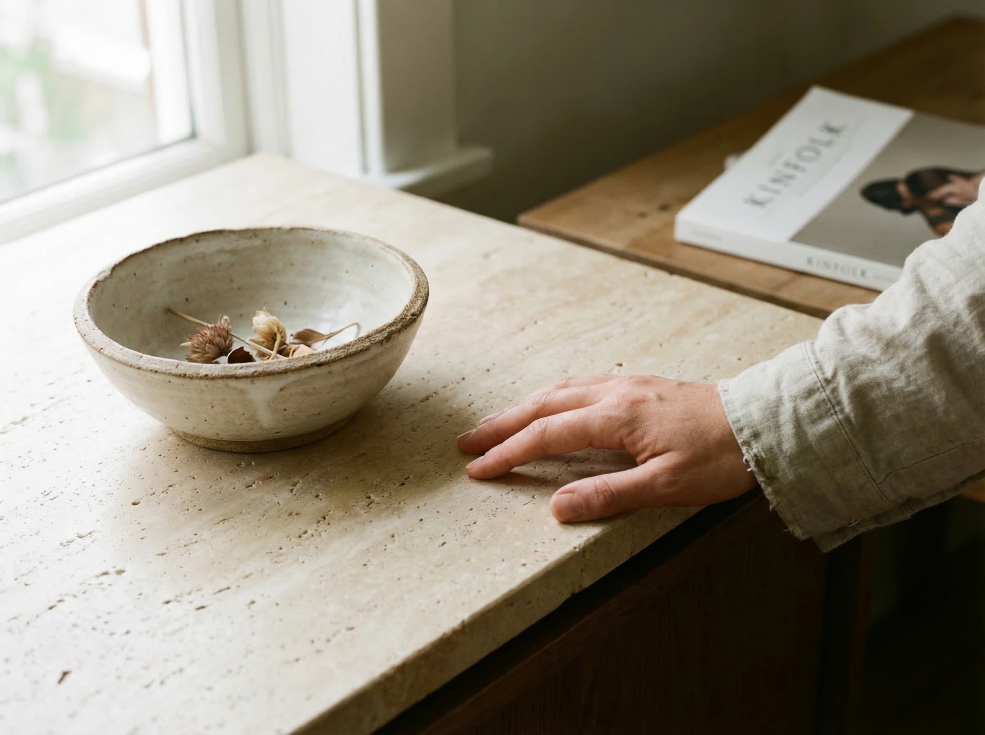 Hand resting on travertine counter with handmade ceramic bowl