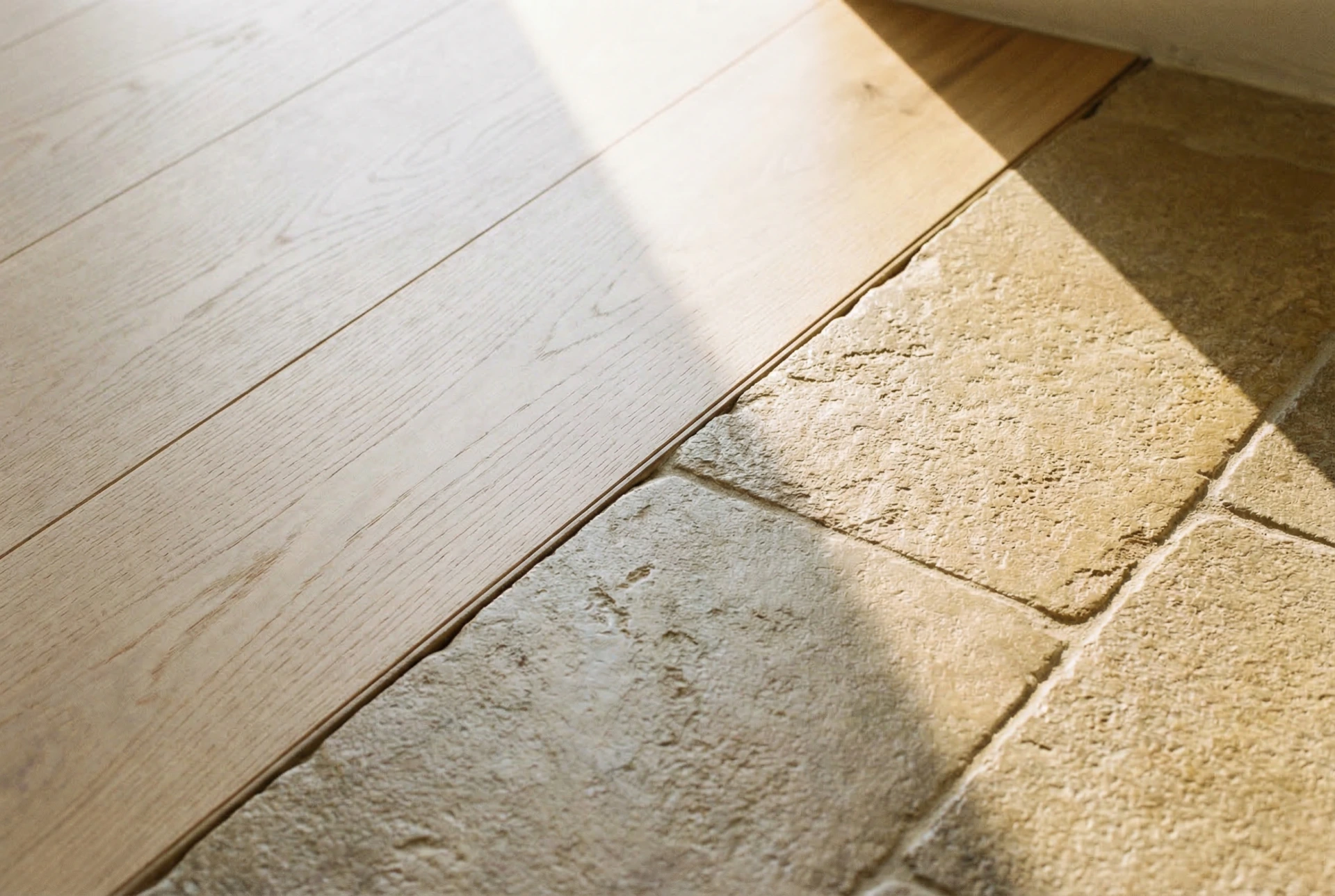 Seamless transition between oak flooring and limestone paving at villa threshold