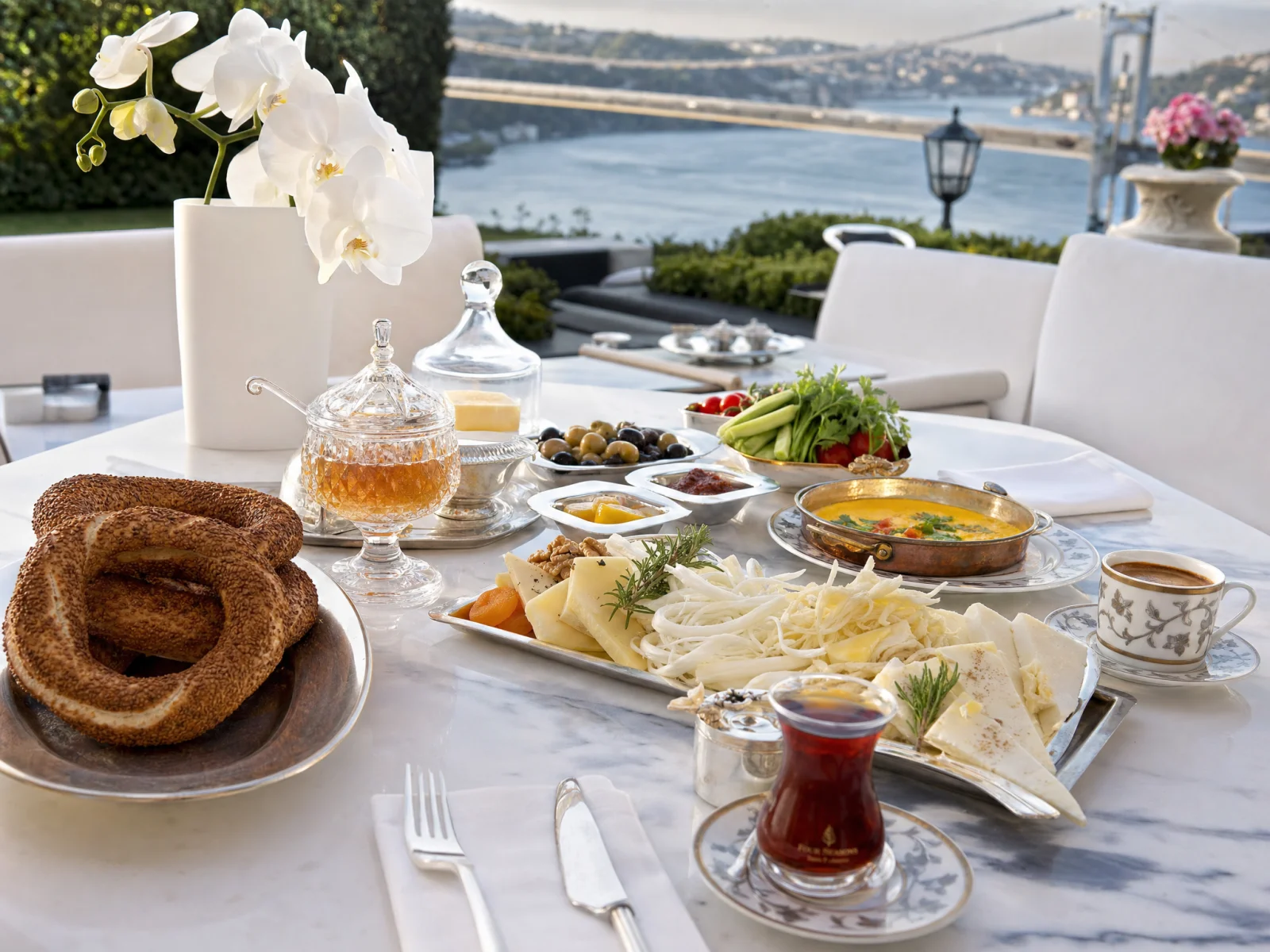 Long Turkish breakfast on a marble terrace overlooking the Sea of Marmara, with simit, white cheese, olives, kaymak, fresh herbs and tea in a tulip glass