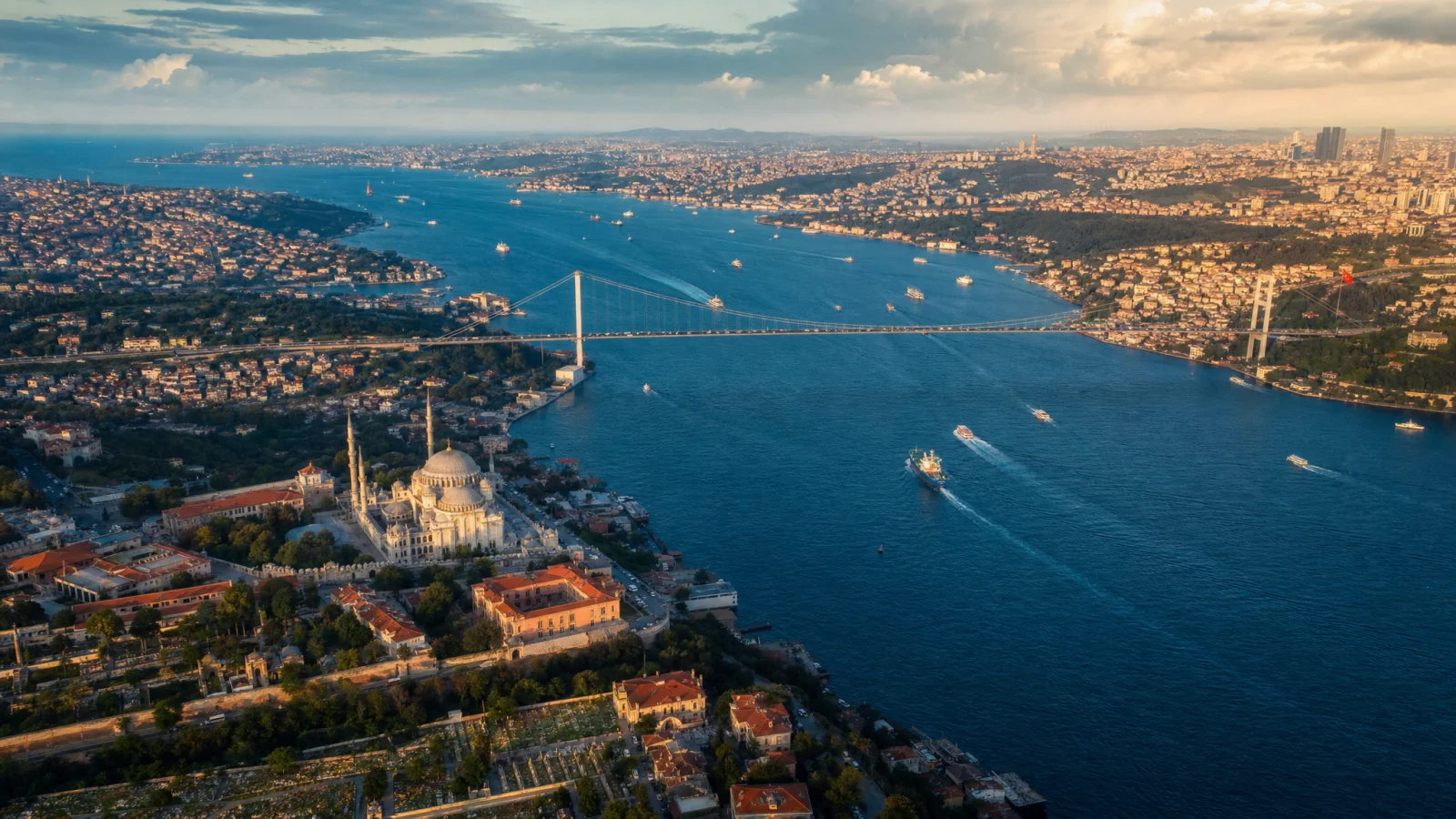 Stylised aerial perspective of the first Bosphorus Bridge connecting the European and Asian sides of Istanbul, with the small white Ortaköy Mosque at the European foreshore and ferries crossing the strait below